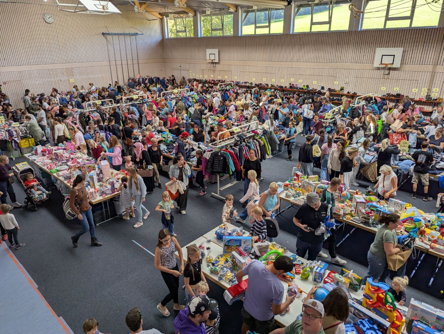Tische mit Spielzeug und Kinderkleidung in der vollen Halle